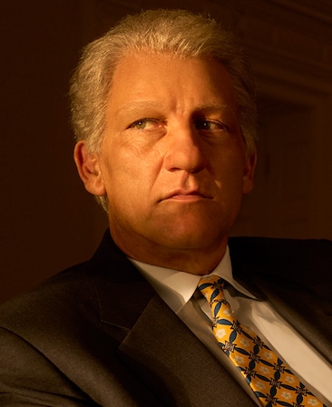 Headshot of Clive Owen as Bill Clinton looking to his right in suit with light shadowing face from FX's American Crime Story