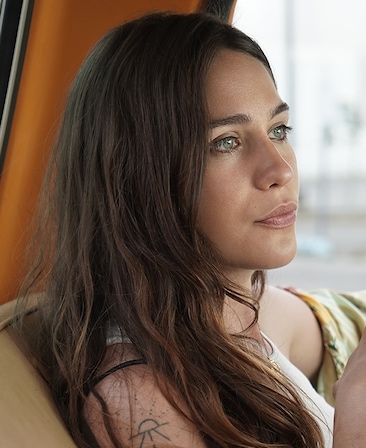 Lola Kirke headshot wearing a white shirt and a tattoo on her shoulder