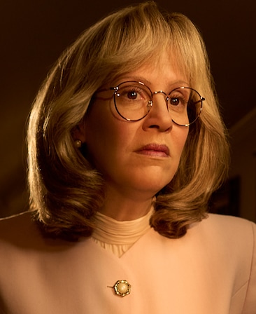 Headshot of Sarah Paulson as Linda Tripp wearing glasses and pink top