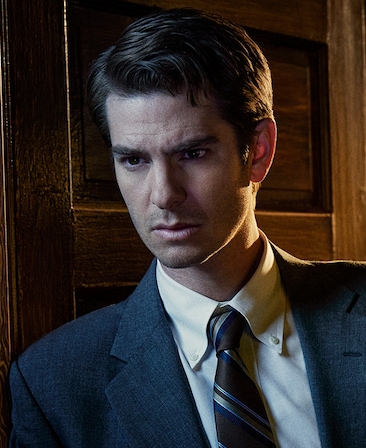 Andrew Garfield headshot wearing a suit leaning against a door