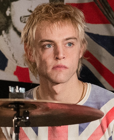 Jacob Slater headshot wearing a British flag shirt behind an instrument