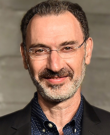 Paul Lee headshot wearing glasses and a polka dot button up with black blazer