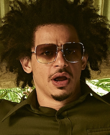 Eric Andre headshot wearing sunglasses and a green button up shirt