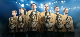 Group of friends lined on up a football field in Fantasy Football sports jackets standing behind golden busts of themselves