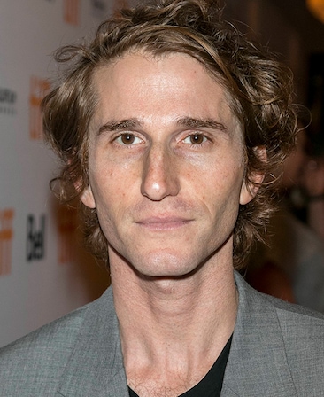 Headshot of Max Winkler, Executive Producer of FX's Grotesquerie, wearing black shirt under a grey suit.