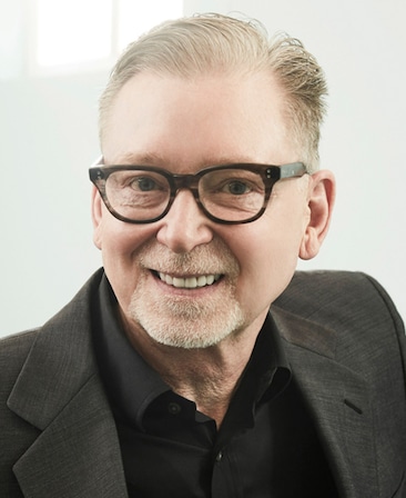 Warren Littlefield headshot wearing a black suit and glasses against a white background