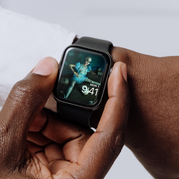 Man wearing Apple Watch with lock screen of doll sitting with doll heads and wearing blue dress FX's American Horror Stories