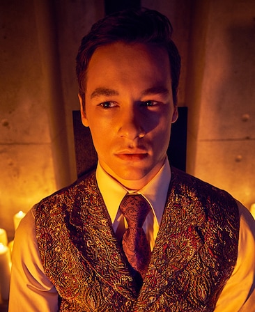 Kyle Allen headshot in patterned vest over white button down with candles illuminating in background from AHS Apocalypse