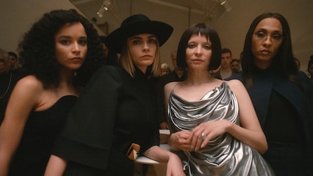 4 women standing next to each other staring into the camera. 