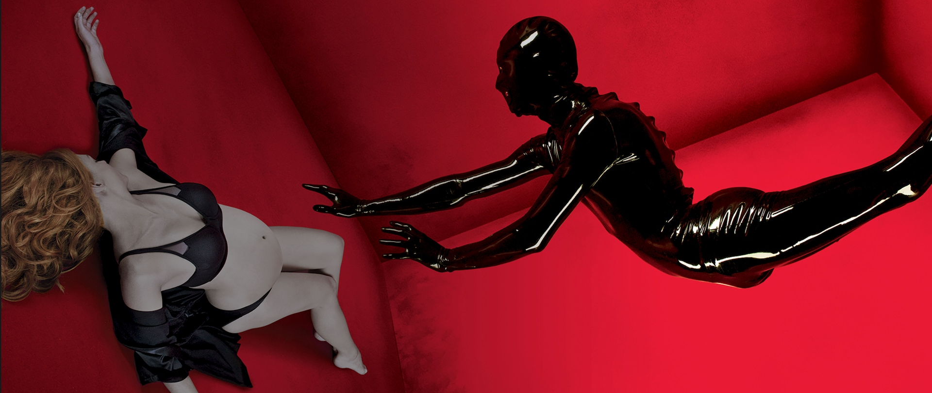Pregnant woman laying on red floor in black lingerie with rubber man reaching toward her for AHS Installment 1 Murder House