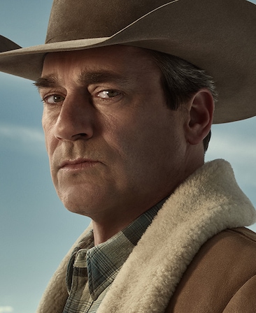 Jon Hamm headshot wearing a cowboy hat and flannel shirt with a fur lined coat over