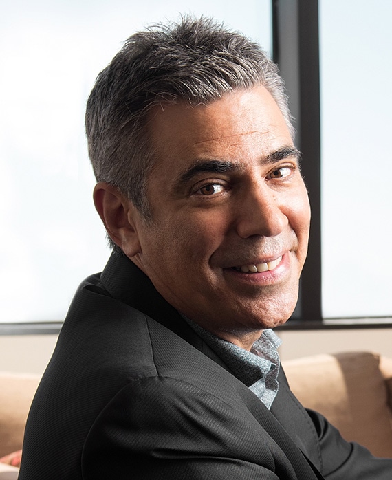 Michael London Headshot wearing a black suit jacket and sitting by a window