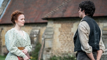 Biddy holding a book and standing outside of a building with Pip