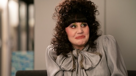 Nadja wearing a silver blouse with a large bow on the collar