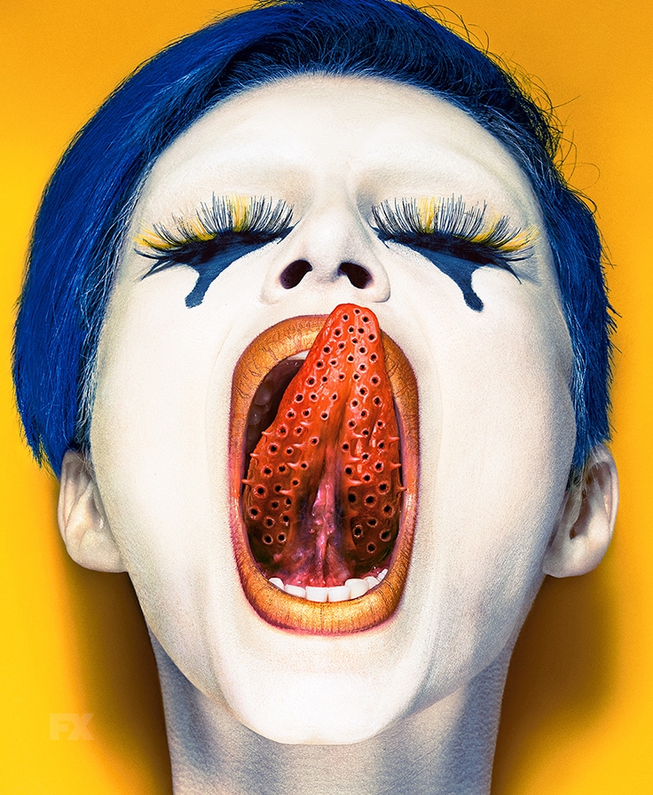 Woman with blue hair and eyeshadow closing eyes and licking lips with holed tongue from FX's AHS Cult