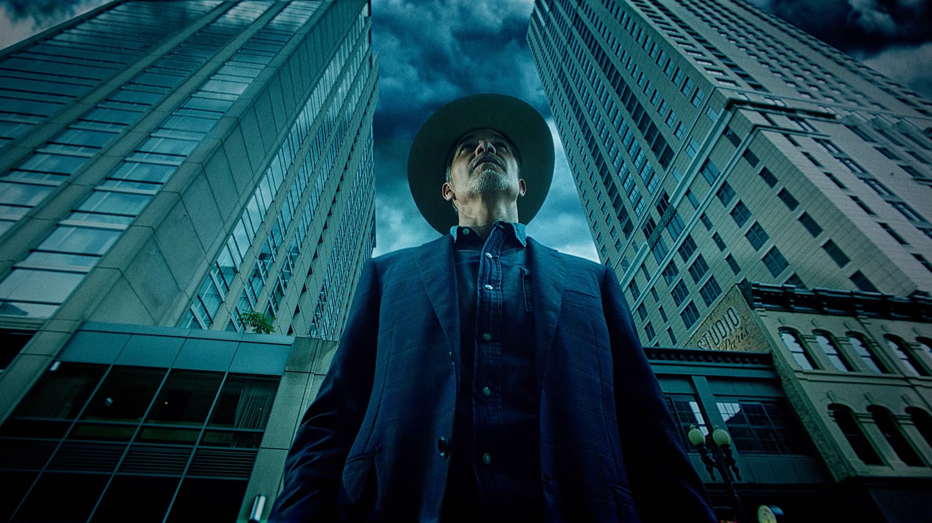 Raylan Givens standing in front of to skyscrapers