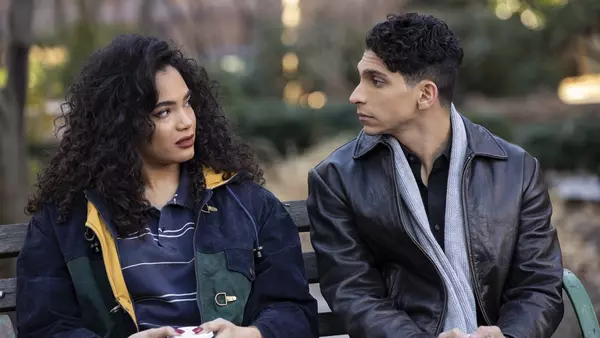 A couple sitting on a park bench, looking at each other