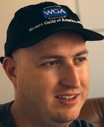 Shawn Ryan headshot wearing a baseball cap that reads "WGA Writers Guild of America"