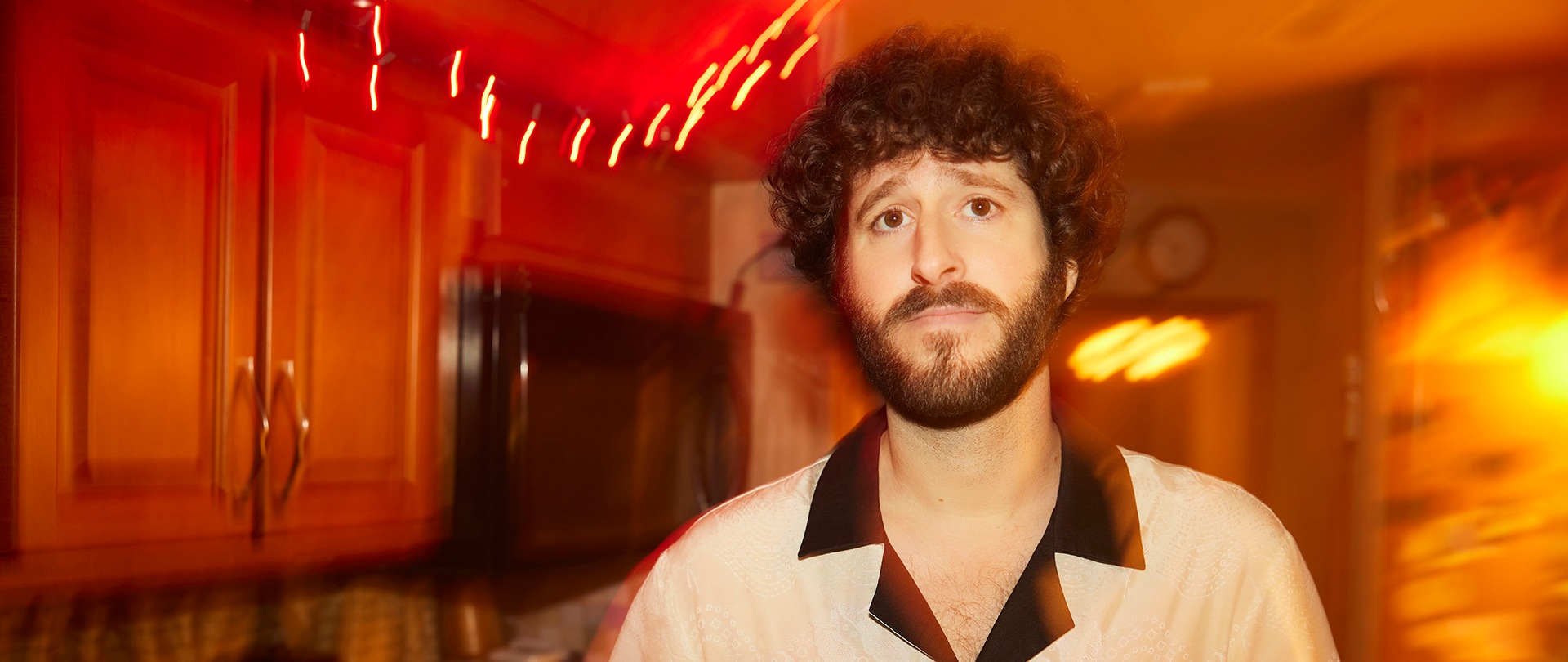 Dave wearing a white and black shirt with a blurry orange background