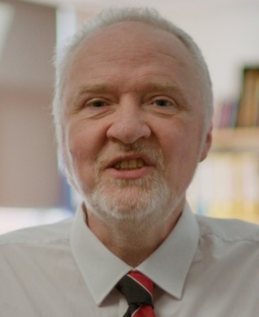Mark Griffiths headshot wearing a white button up and red and black tie