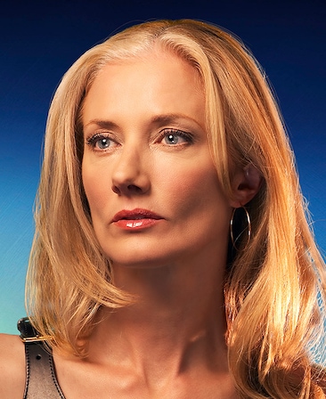 Joely Richardson headshot wearing a black top with a buckle strap and hoop earrings