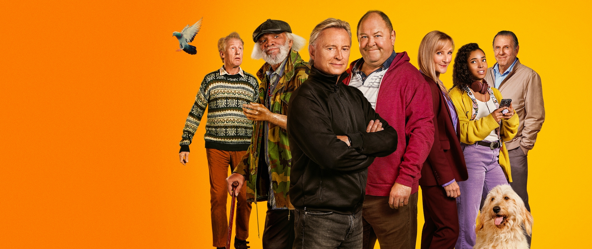 Cast of Full Monty in casual outfits for fall weather standing in front of an orange ombré background.