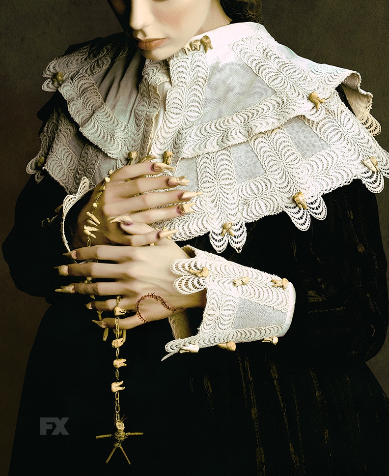 A person in pilgrim attire holding a necklace made of human teeth.