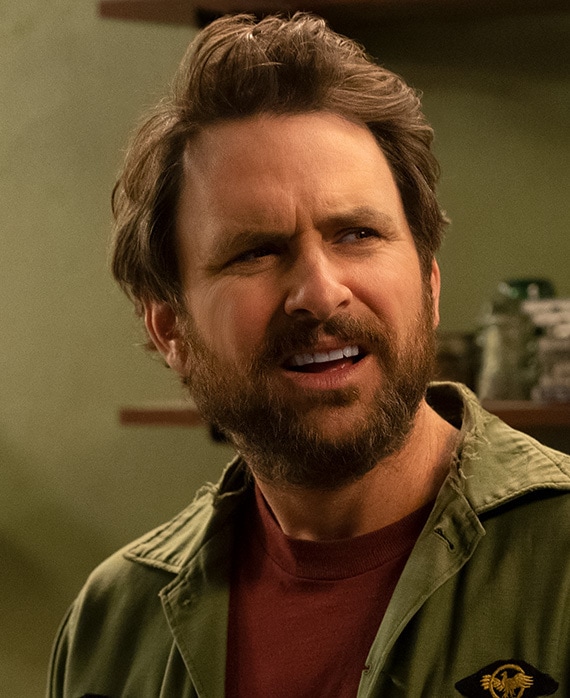 Charlie Day headshot wearing a green jacket and red shirt
