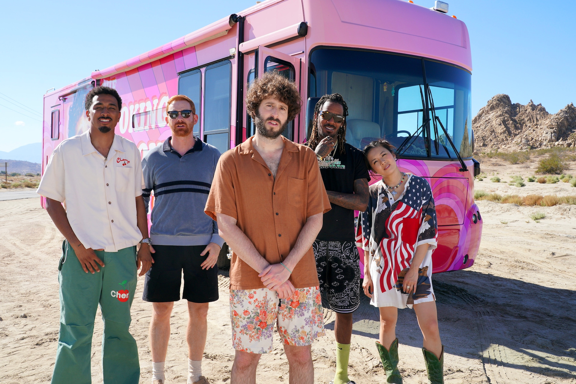 DAVE cast standing in front of pink tour bus in the desert