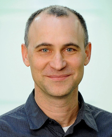 Joel Fields headshot wearing a navy striped collar shirt