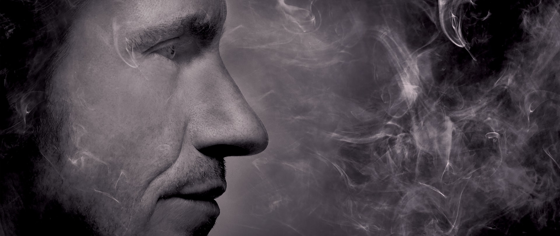 Grayscale close-up side profile of Denis Leary with smoke plumes surrounding his face for FX's Rescue Me
