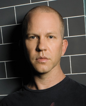 Ryan Murphy headshot wearing a black shirt standing against black brick wall