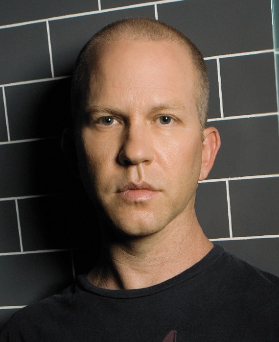 Ryan Murphy headshot wearing a black shirt standing against black brick wall