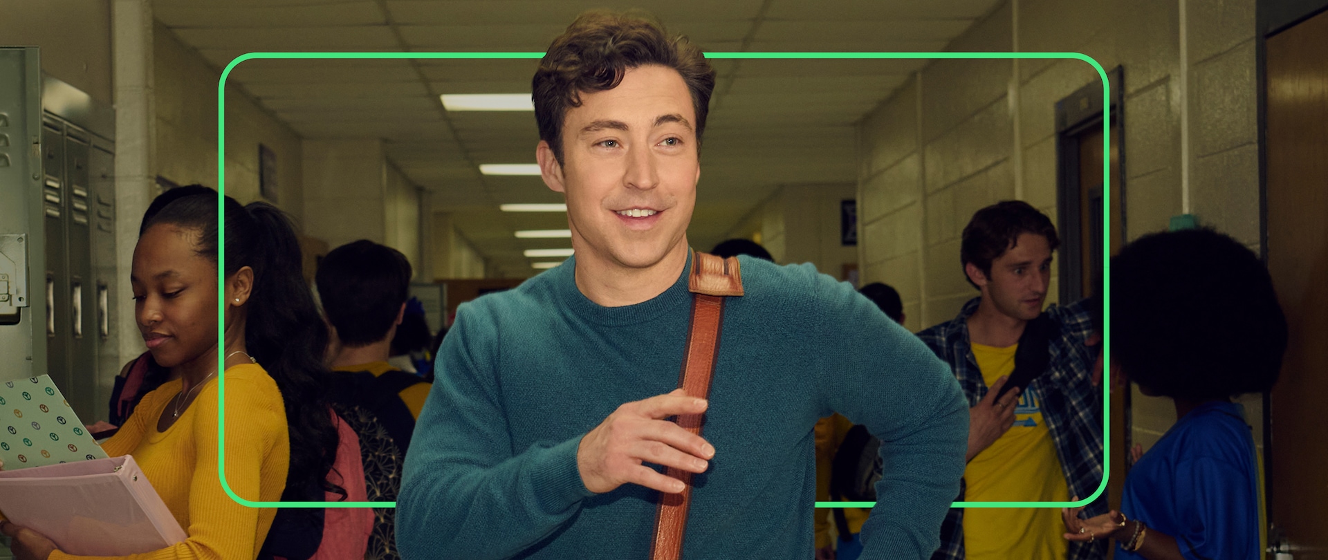 Close up of Teacher Evan wearing a dark blue sweater and a brown satchel.