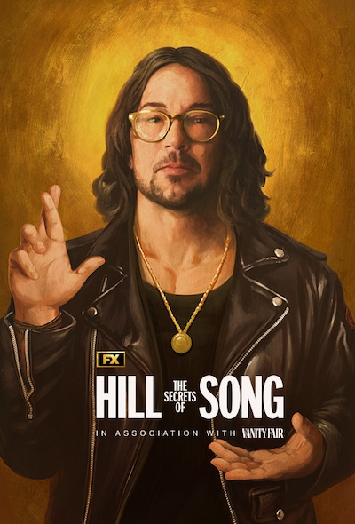 Man wearing a gold chain and black jacket while holding his hand up and crossing his fingers for FX's The Secrets of Hillsong