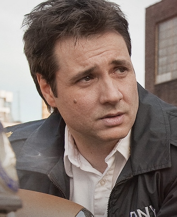 Adam Ferrara headshot wearing a white shirt and fire jacket while outside
