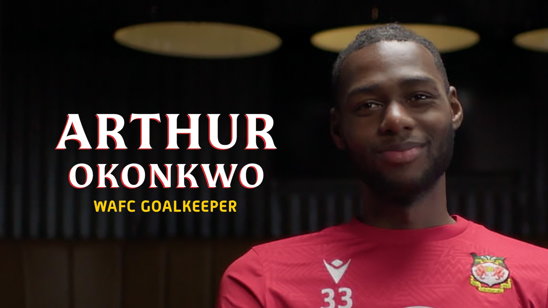 Arthur Okonkwo headshot in a red WAFC tshirt in a dimly lit room, with his name in large white text lined in red.