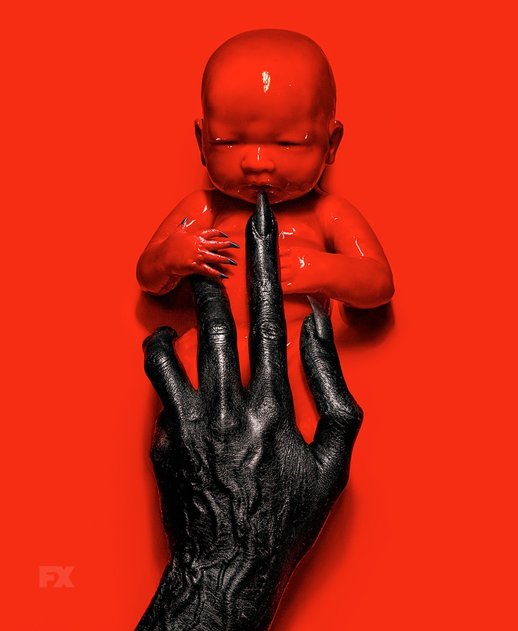Red baby with black claws held by black hands American Horror Story 8 Apocalypse
