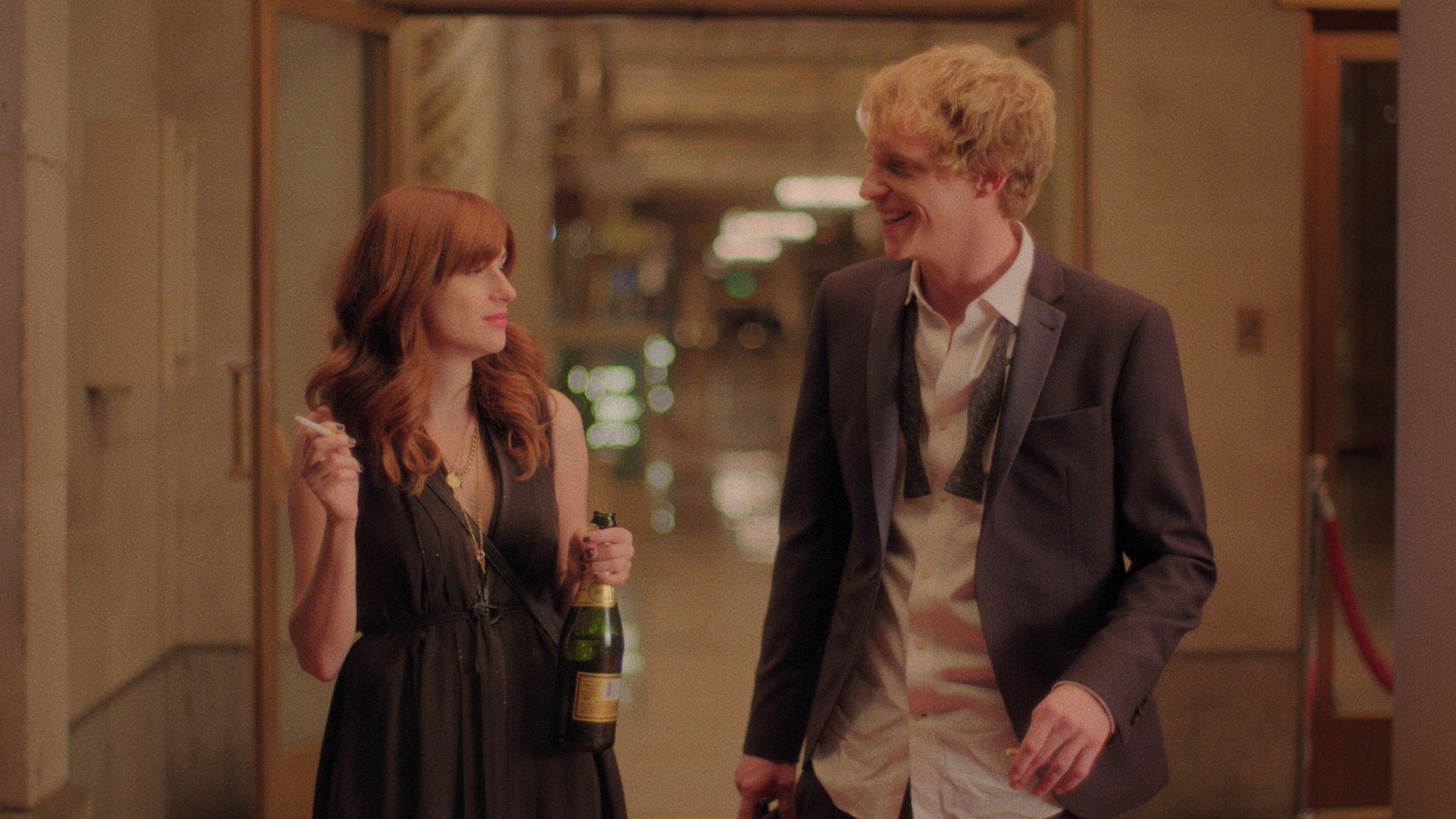 Jimmy in an undone suit and Gretchen holding a bottle and smoking for You're The Worst