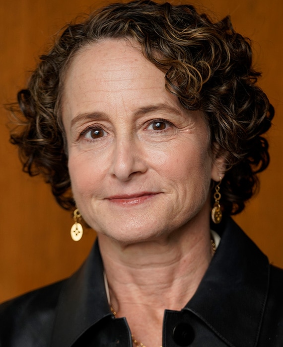 Headshot of executive producer Nina Jacobson of FXs Love Story wearing a black blouse and gold jewelry.
