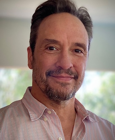 Headshot of executive producer D.V. DeVincentis in FX's Love Story in a pink button up.