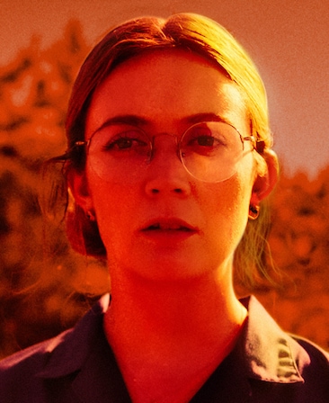 Headshot of Billie Lourd in black shirt with red lighting covering face