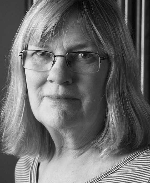 Black and white headshot of Mary Rae Thewlis wearing glasses in striped t shirt