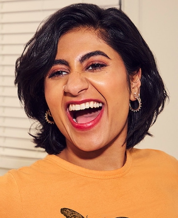 Headshot of Amita Rao as Issa in FX's Adults yellow shirt with gold jewelry, laughing at the camera.