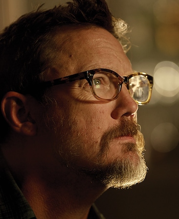 Mathew Lillard headshot of side profile with blurred lights in background and light slightly shining down on shadowed face