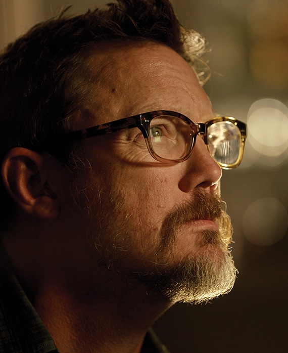 Mathew Lillard headshot of side profile with blurred lights in background and light slightly shining down on shadowed face