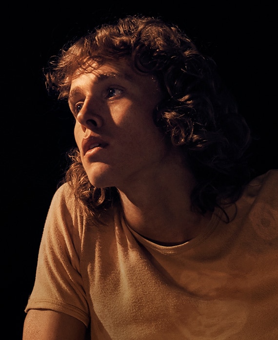 Harris Dickinson Headshot wearing an orange shirt 