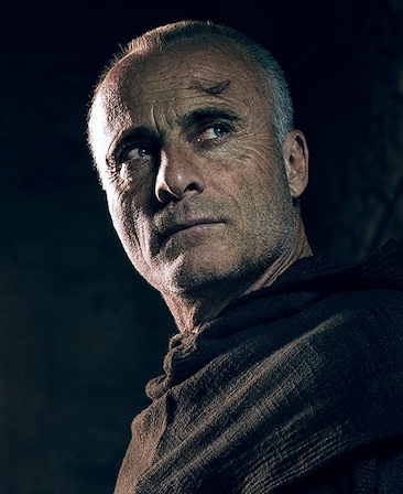 Timothy V. Murphy headshot in layered black robe cloaked over shoulder with scar wound over his left forehead