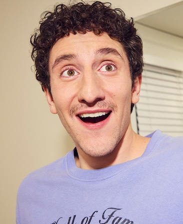 Headshot of Malik Elassal as Samir in FX's Adults, wearing a purple crew neck smiling at the camera.