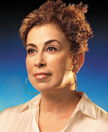 Roma Maffia headshot wearing a white shirt and hoop earrings